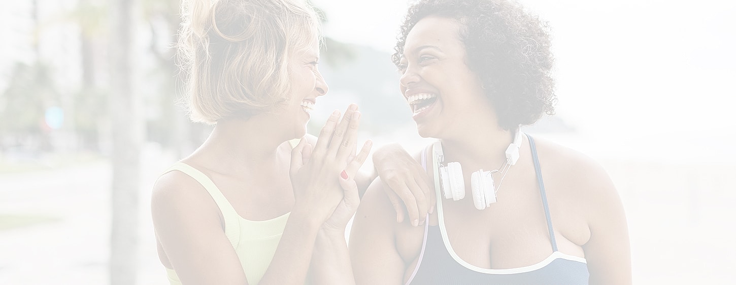 Two women laughing together outdoors.