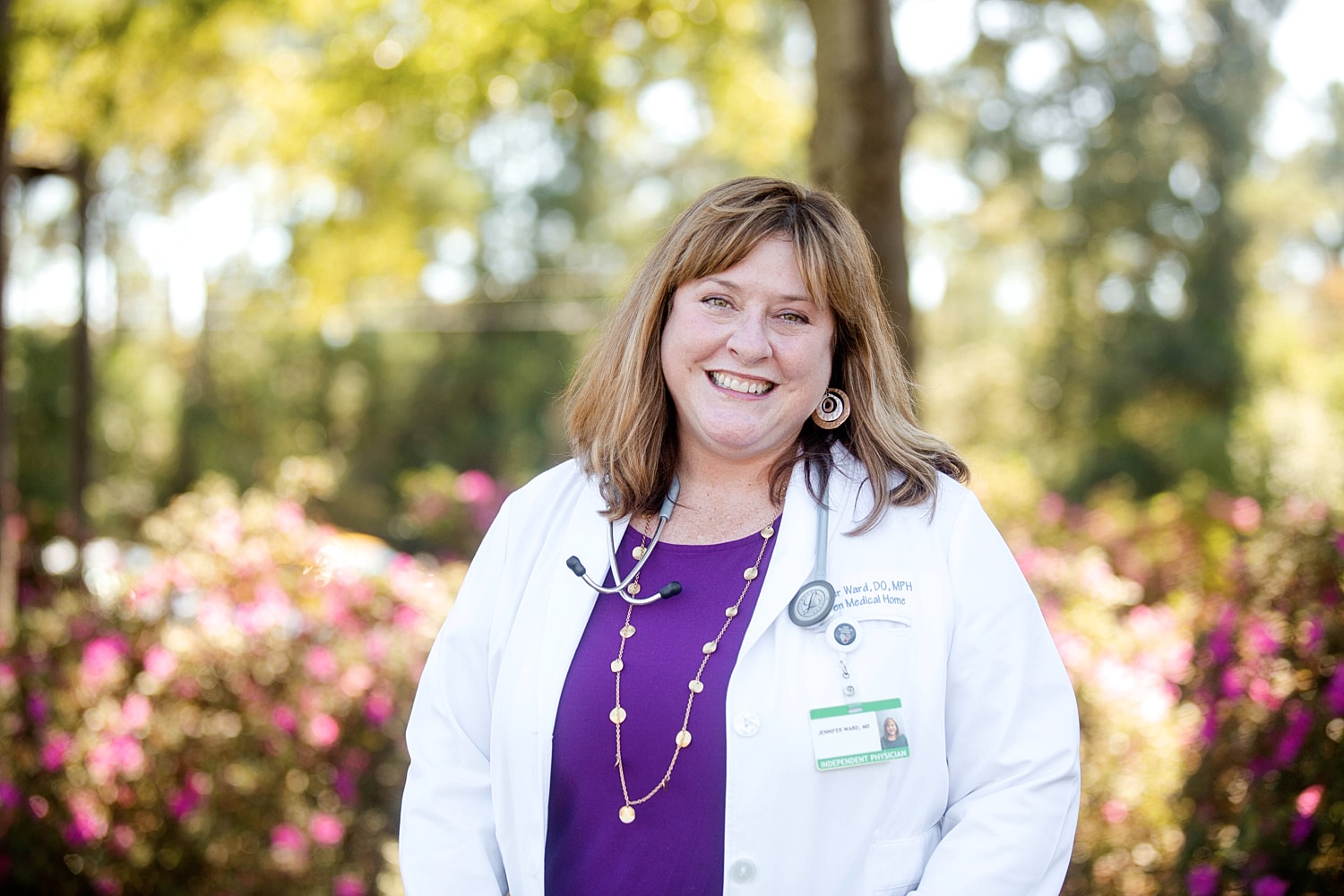 Smiling doctor in white coat outdoors.