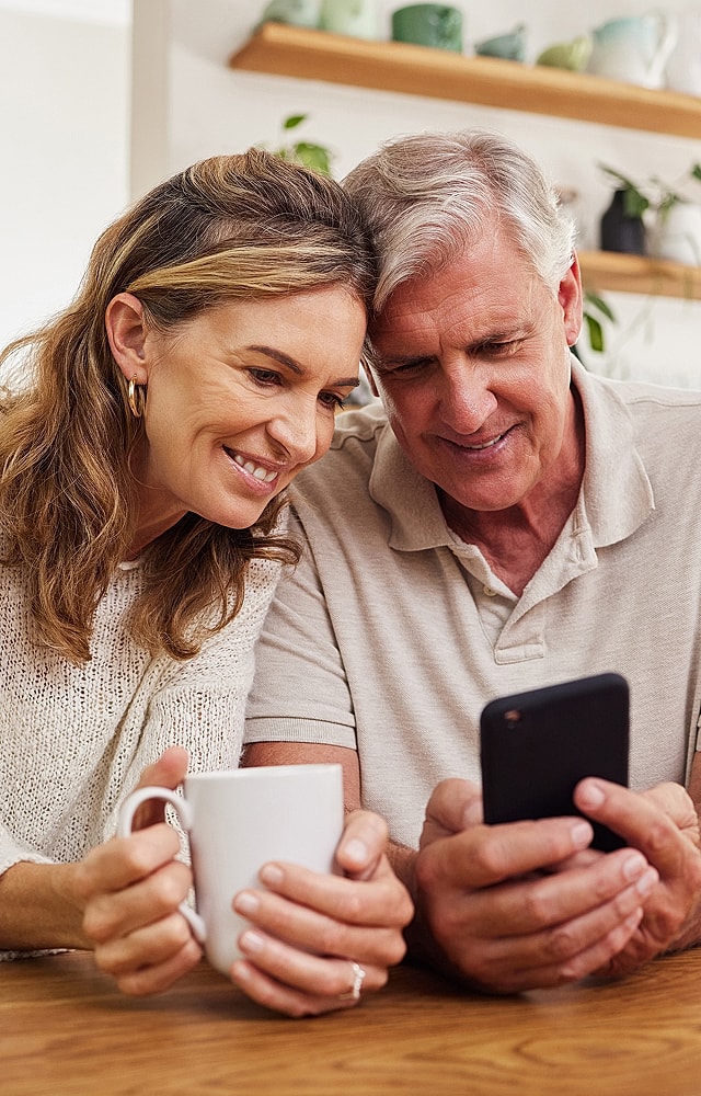 Couple enjoying coffee and looking at phone.