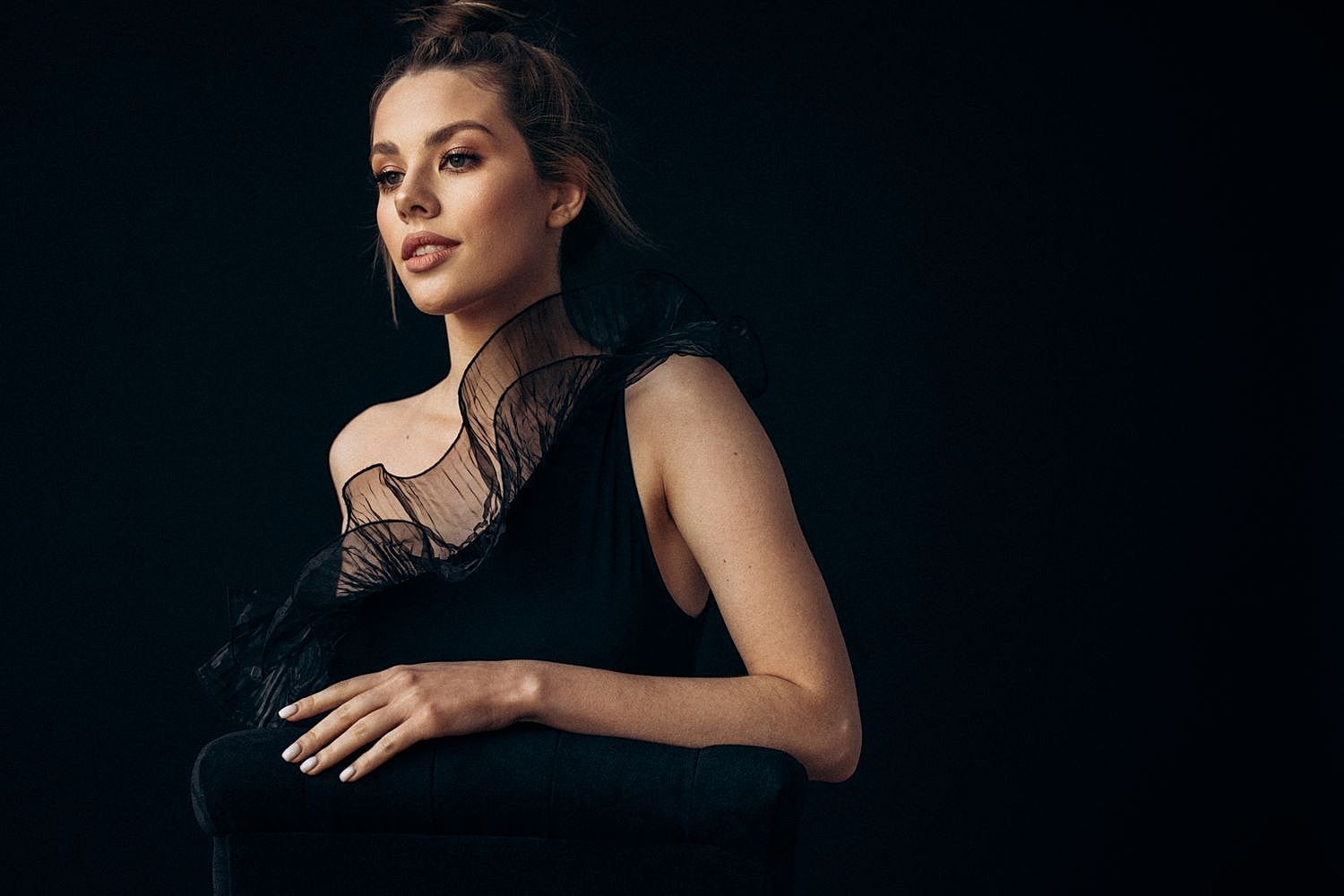 Woman in black dress against dark background.