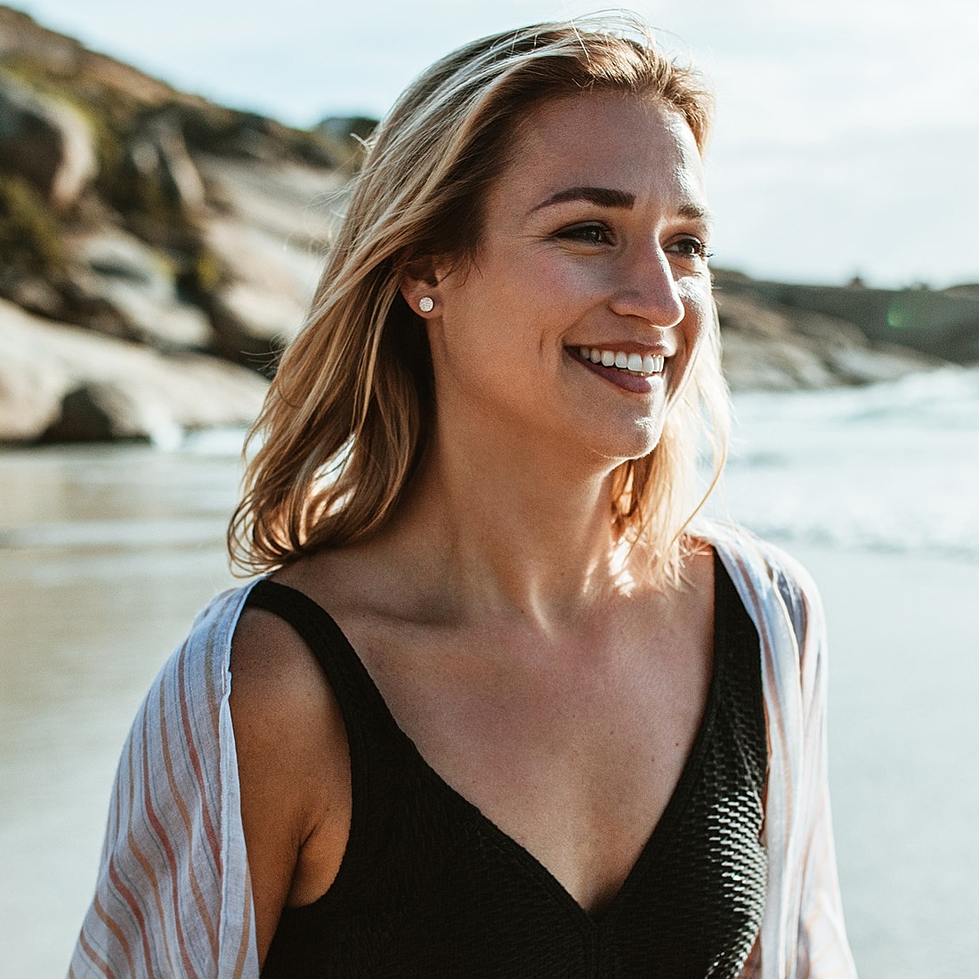 Smiling woman walking on beach with waves.