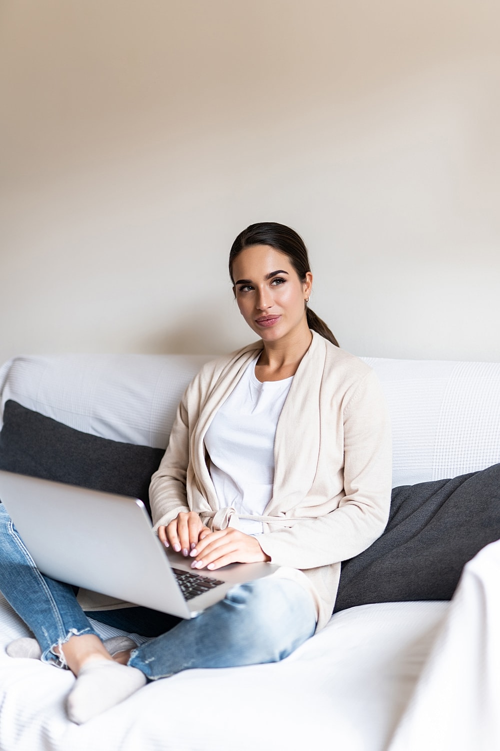 Woman with laptop relaxing on a couch.