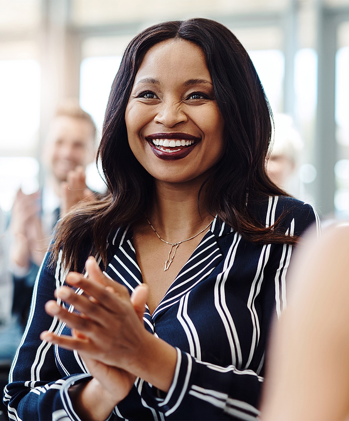 Smiling woman clapping in a business setting.