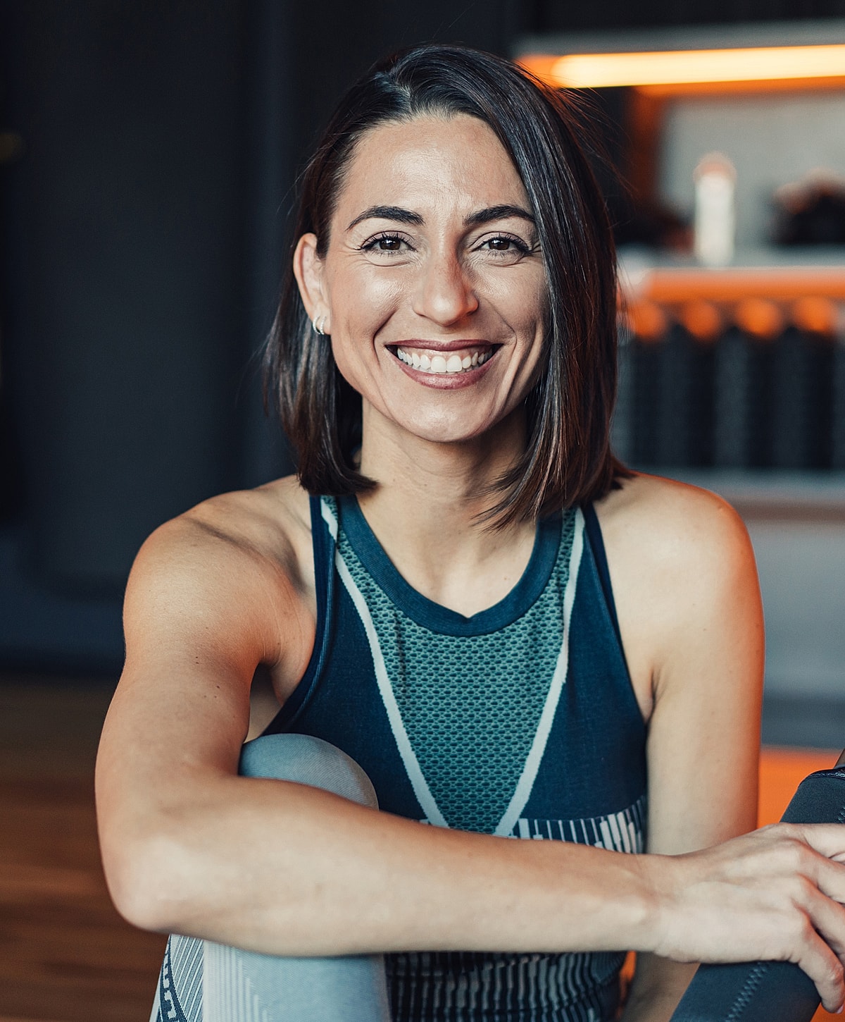 Smiling woman in athletic wear, fitness studio setting.