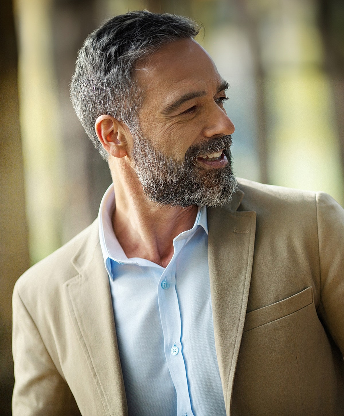 Smiling man in a light jacket outdoors.