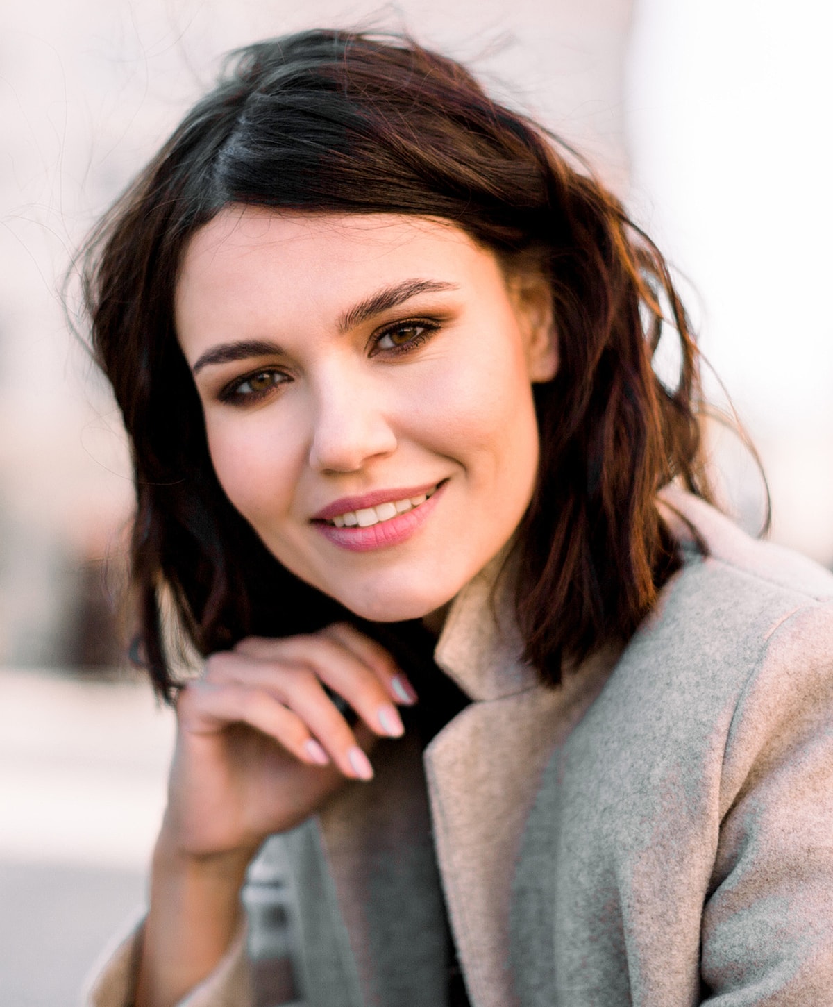 Smiling woman with brown hair in outdoor setting.