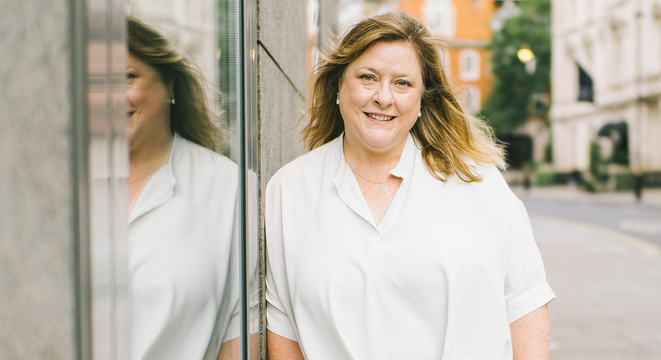 Smiling woman leaning against a reflective surface.