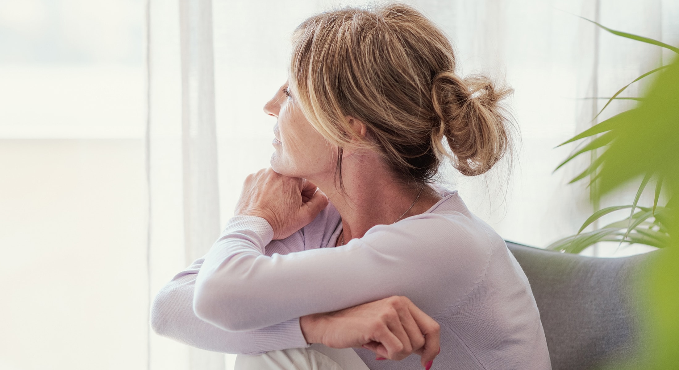 Woman sitting thoughtfully by a window.